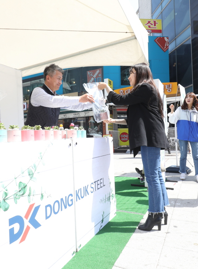 장세욱 동국제강 부회장이 철의 친환경성을 홍보하기 위한 ‘그린 캠페인’ 일환으로 임직원들과 15일 서울 마포에서 한 시민에게 철로 만든 미니 화분을 나눠주고 있다.